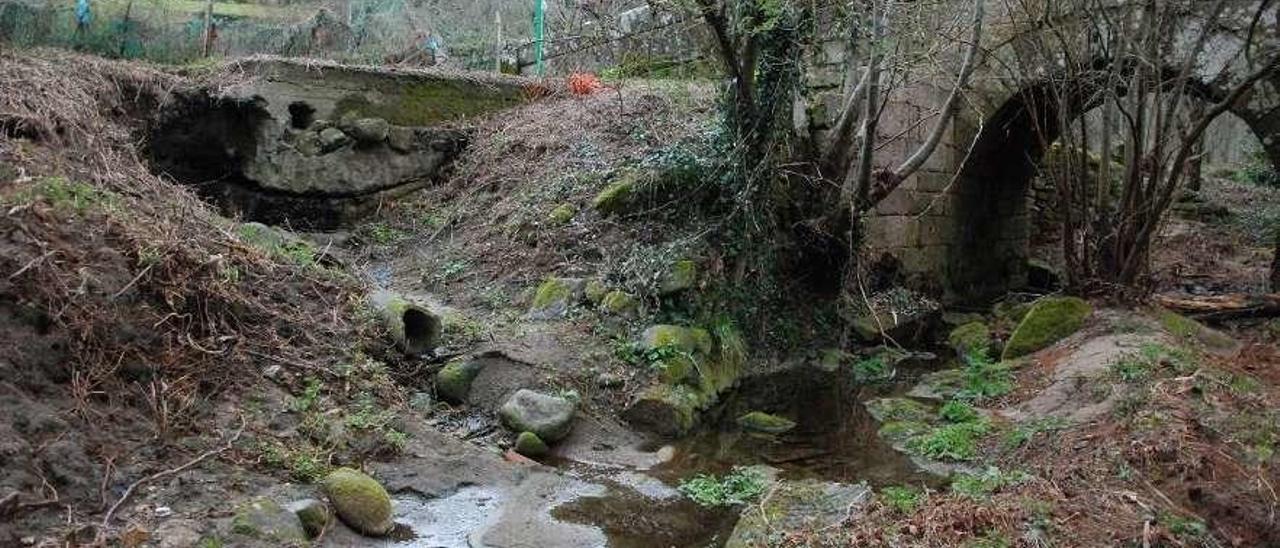 Unha estragada arqueta de decantación verte ludro ao pé da ponte.