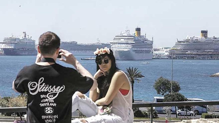 Una pareja se fotografía con la bahía de Palma de fondo, con varios cruceros en el horizonte.