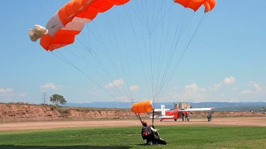 Un paracaigudista aterrant a l&#039;aeròdrom de Sant Fruitós amb l&#039;avió al fons
