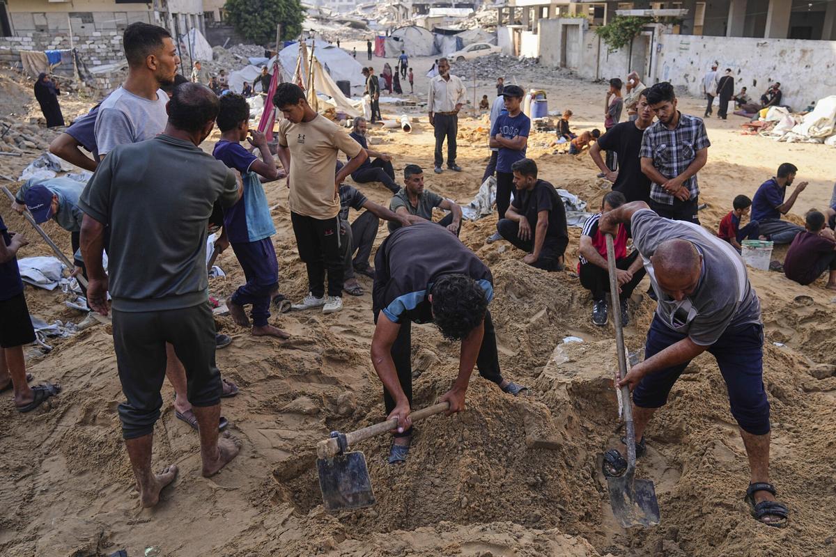 Palestinos excavan en la arena buscando sus pertenencias tras un ataque israelí contra un campamento de desplazados en la ciudad de Gaza, el sábado 28 de junio de 2025. (Foto AP/Jehad Alshrafi)