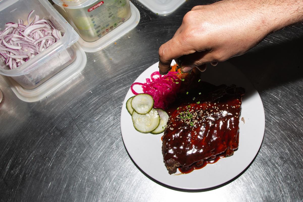 El cocinero de Kitchen 154, en el Mercado de Vallehermoso, decora unas costillas coreanas.