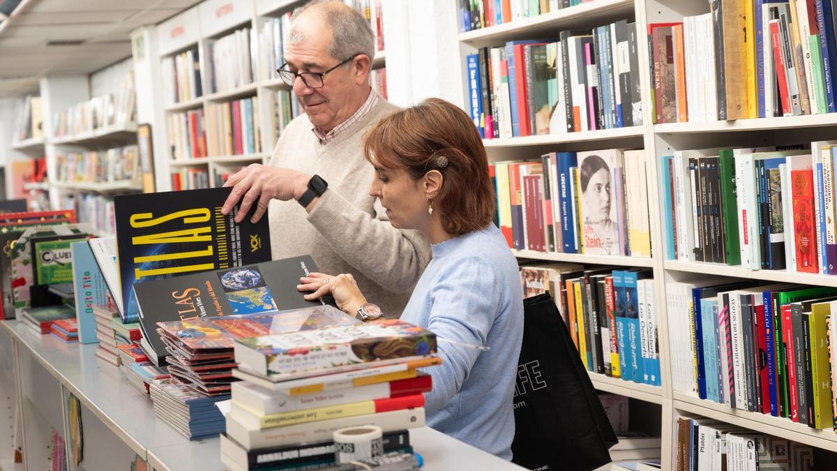 Dos clientes de la librería París de Zaragoza ojean un par de libros.