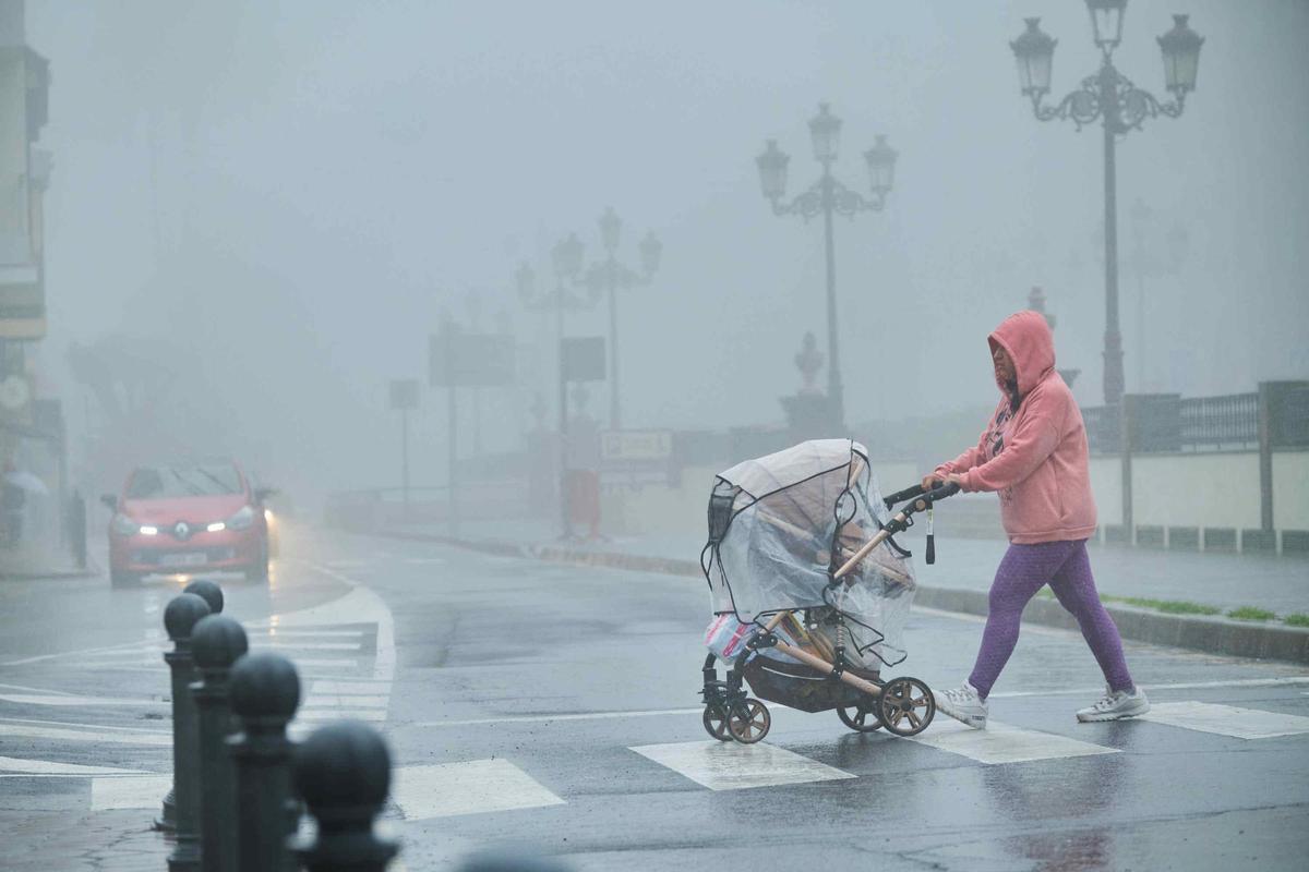 Una mujer pasea bajo la lluvia de una tormenta en Canarias.