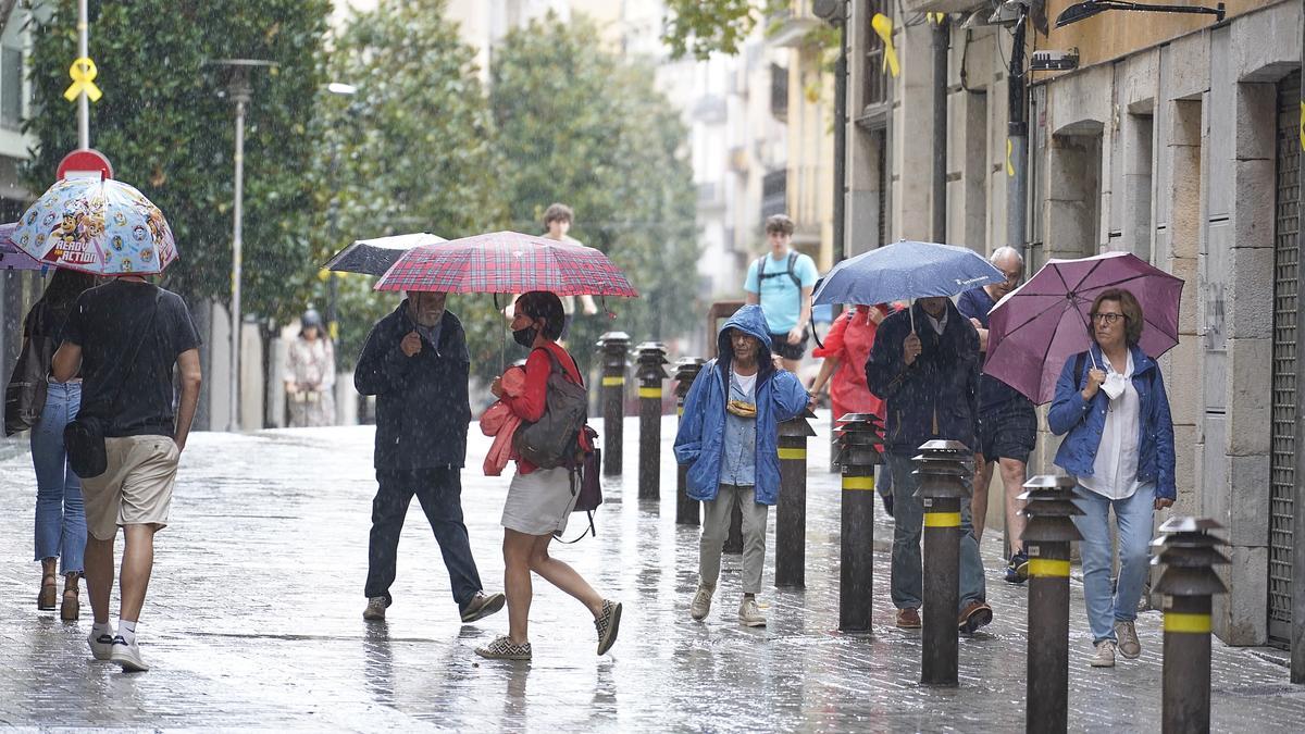 Gent amb paraigües durant un episodi de pluges a Girona