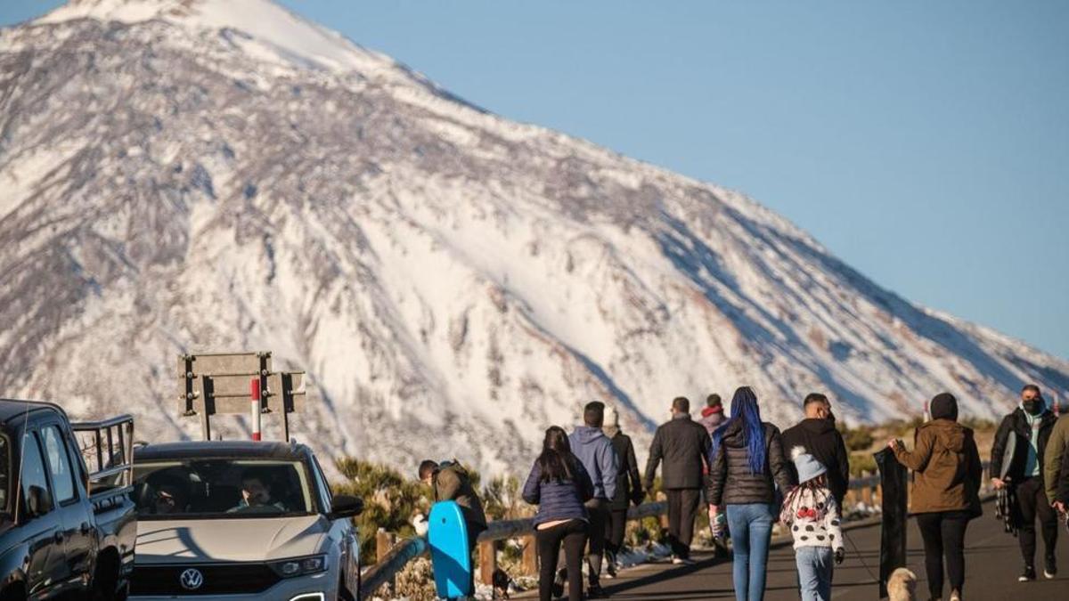 Vehículos en los márgenes de la carretera y un nutrido grupo de personas durante un día de nevada en el Parque Nacional del Teide.