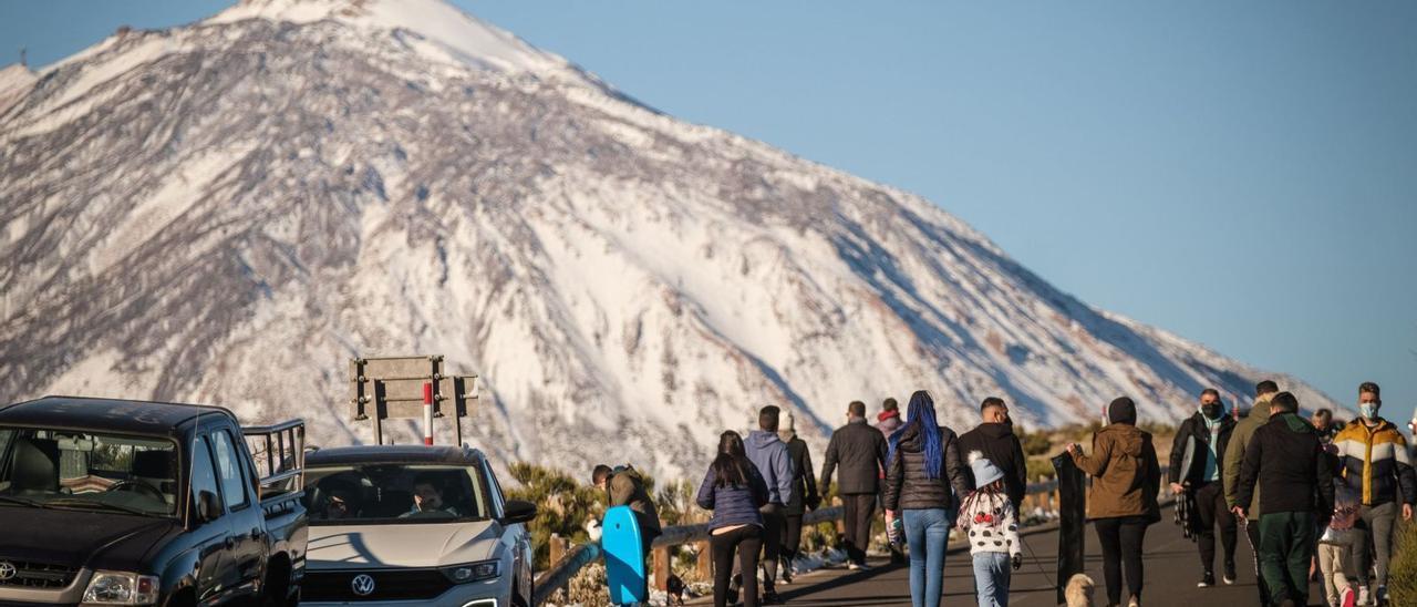 Vehículos en los márgenes de la carretera y un nutrido grupo de personas durante un día de nevada en el Parque Nacional del Teide.