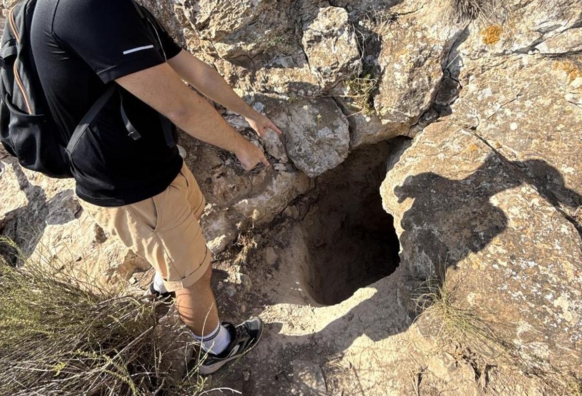 Un excursionista señala el agujero por el que hay que meterse para llegar al arco natural de Bolnuevo