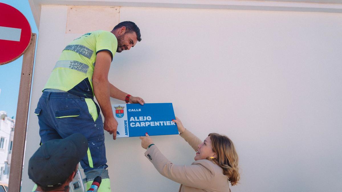 Astrid Pérez alcanza a un operario una de las nuevas placas de calles de Arrecife.