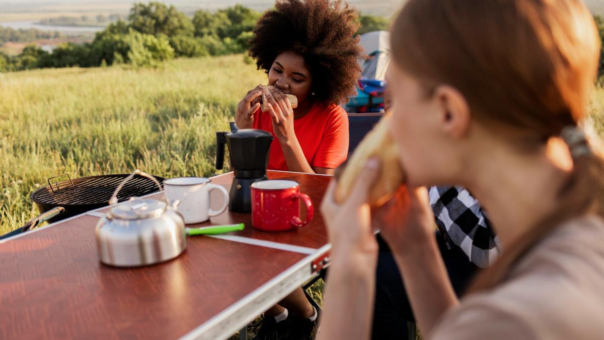 Dos mujeres meriendan en mitad de la naturaleza.