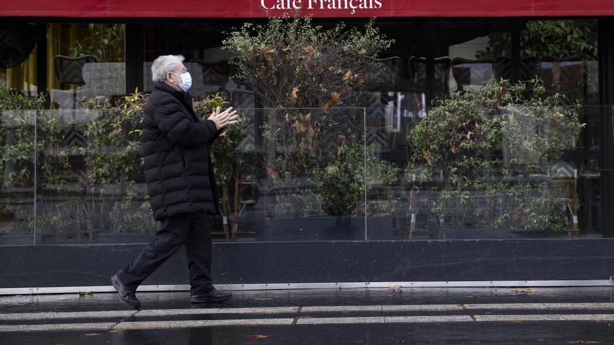 Un parisino camina frente a un café cerrado debido a las restricciones por el coronavirus.