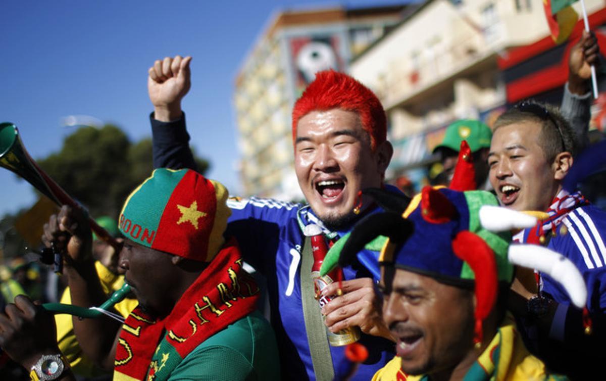 Un aficionat camerunès posa amb japonesos, abans del partit que van disputar les dues nacions.