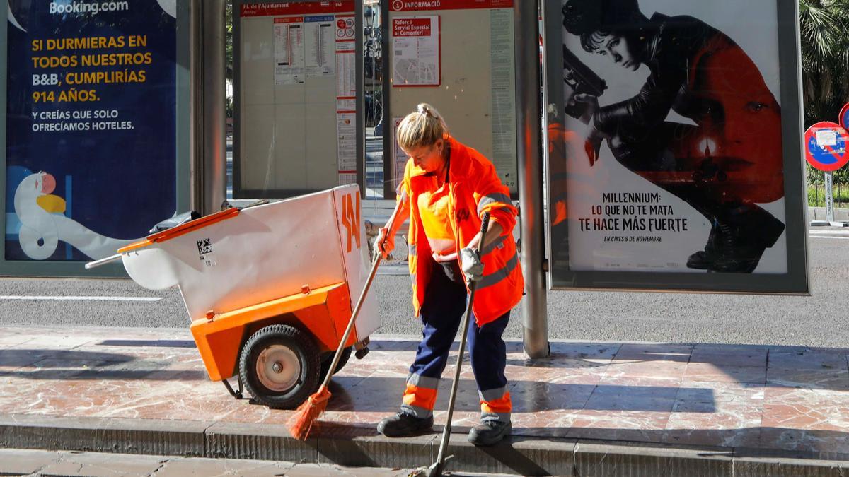 Una trabajadora de SAV, barriendo junto a una marquesina.