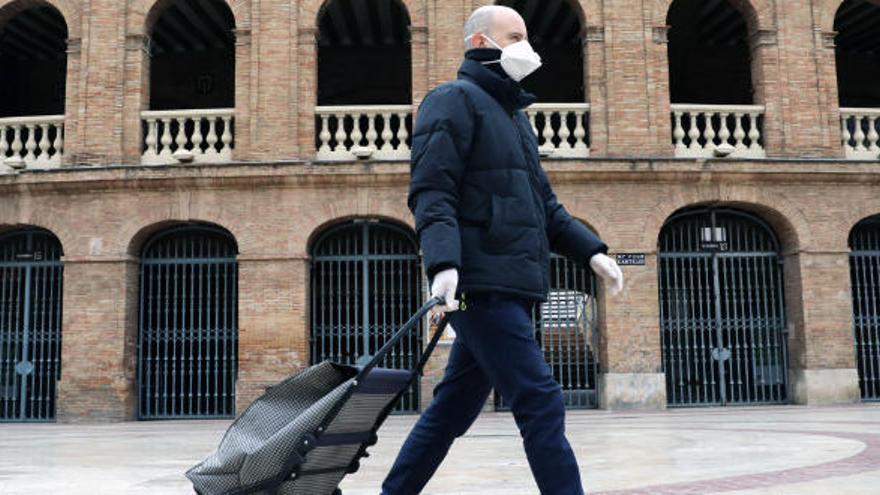 Un hombre con mascarilla camina junto a la plaza de toros de València.