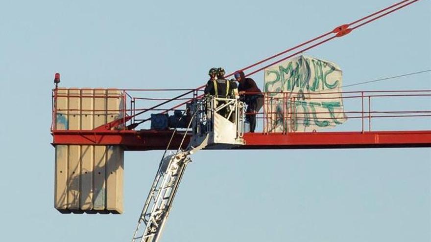 Unos bomberos facilitan alimentos y agua a los activistas encaramados a las grúas.