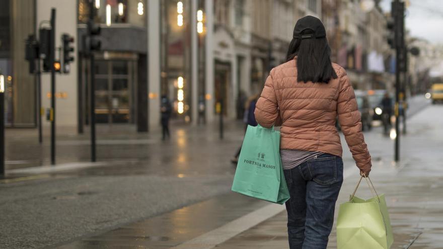 Una mujer camina con bolsas por una calle de Londres.