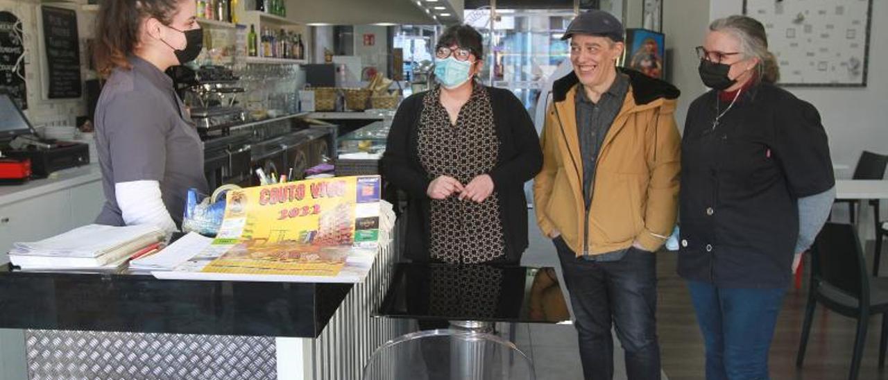 Comerciantes posando con el calendario de 2022 que repartieron por todo el barrio, en el Bar Paparazzi. |   // IÑAKI OSORIO