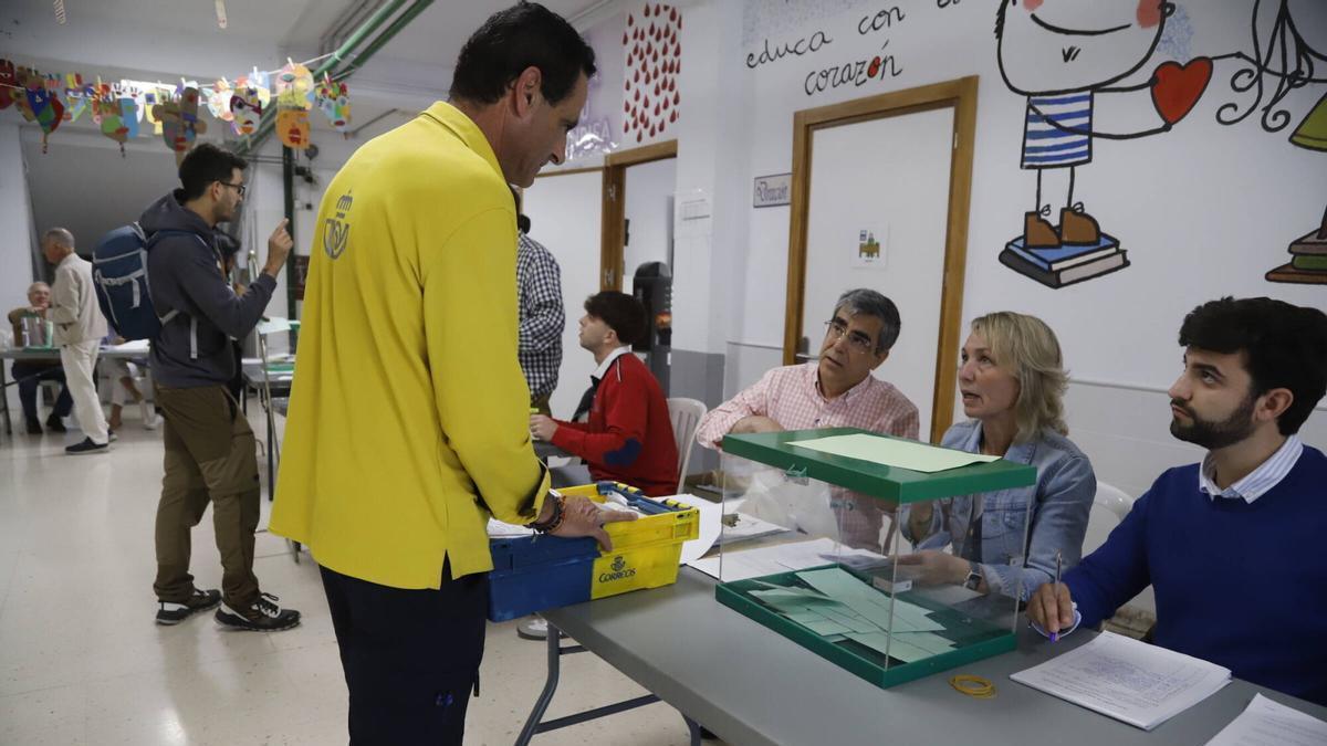 Un funcionario de correos deposita las papeletas del voto por correo en una mesa electoral de Córdoba.