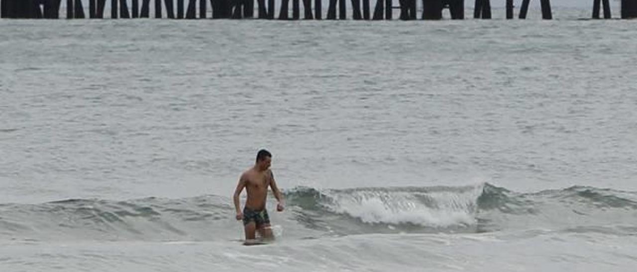 Un vecino bañándose en la playa ayer en pleno temporal.