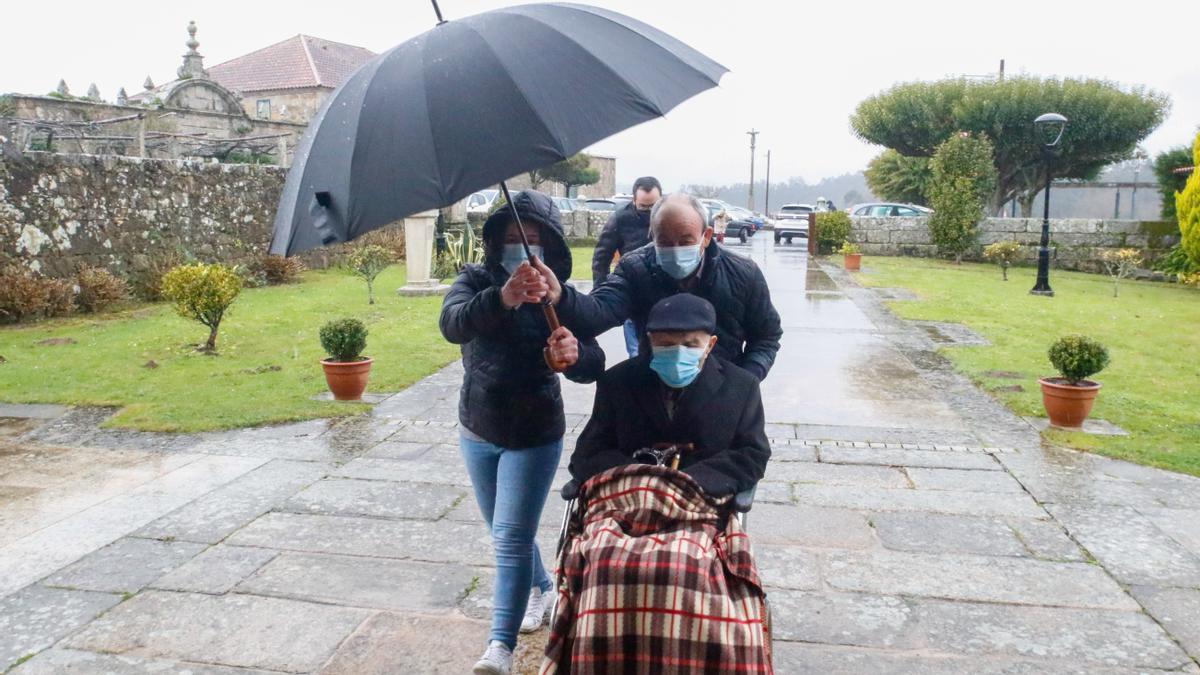 Dositeo Valiñas, en silla de ruedas, llega a la iglesia de Ribadumia, en una jornada marcada por el mal tiempo