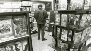 Un cliente, rodeado de estanterías llenas de películas en un videoclub de Barcelona, en 1991.