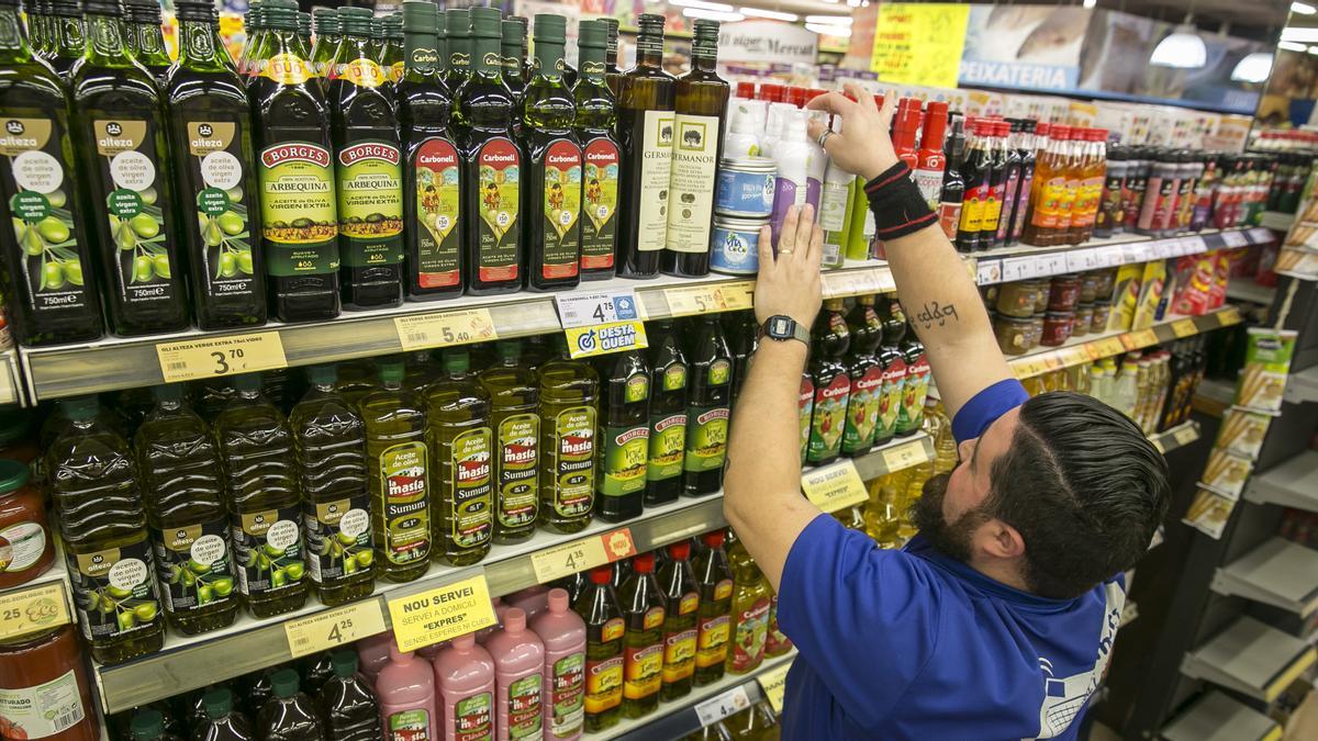 Un dependiente repone botellas de aceite en un supermercado de Barcelona.