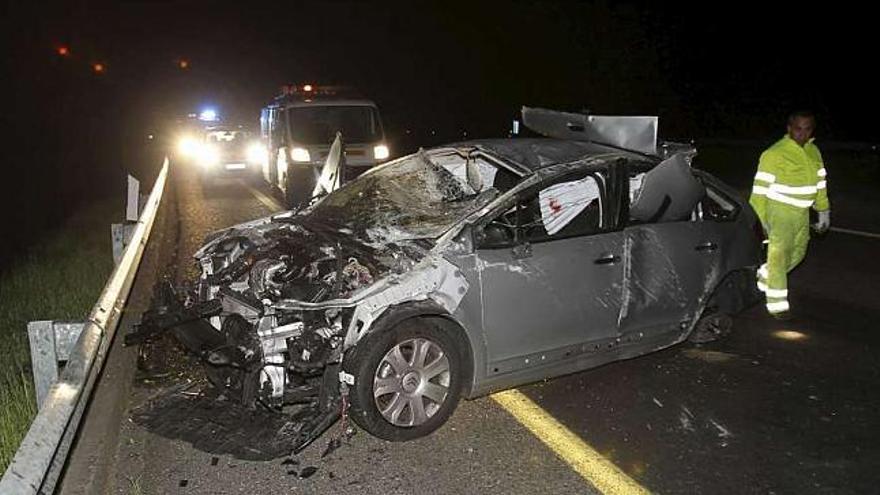 Operarios del servicio de emergencia inspeccionan el coche accidentado en la A-52. / sxenick