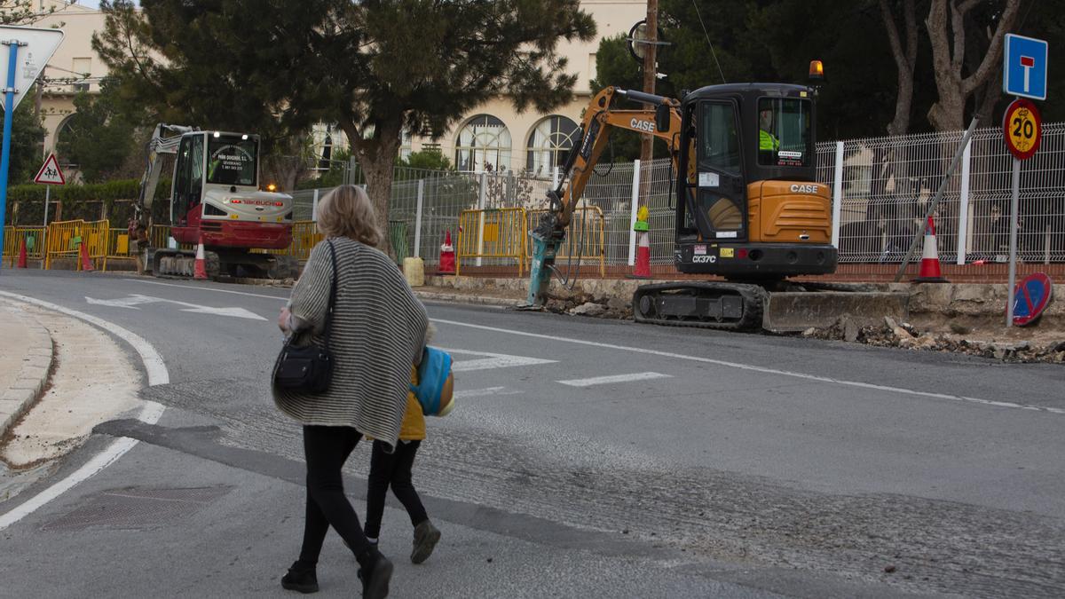 Una mujer y una niña cruzan por una carretera junto a un cole en Alicante