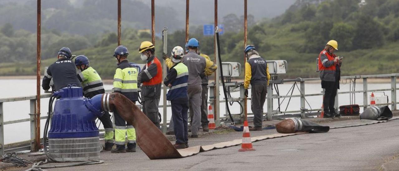 Operarios en la cabecera del embalse junto a una de las bombas con las que se achica el agua. | Marcos León