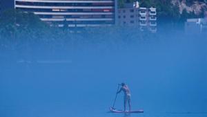 Un hombre practica padel surf en la playa de la Malagueta (Málaga) en medio de la niebla, el pasado día 19.