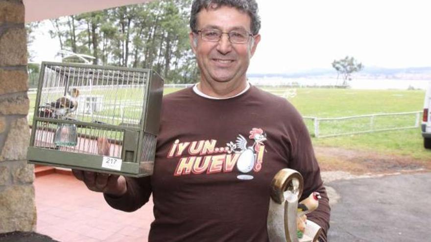 Un concursante de la pasada edición, con su pájaro y su premio. Detrás, los campos de tiro.  // Muñiz