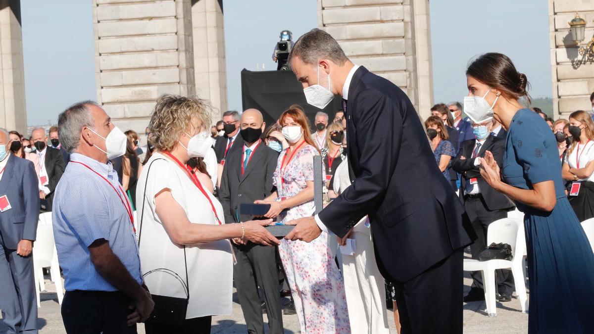 El Rey le entrega la medalla al mérito a la madre de Pablo Riesgo, Montserrat Rivero, con un emocionado Luis Manuel Riesgo, padre del joven, al lado; detrás del Rey, la Reina Letizia.