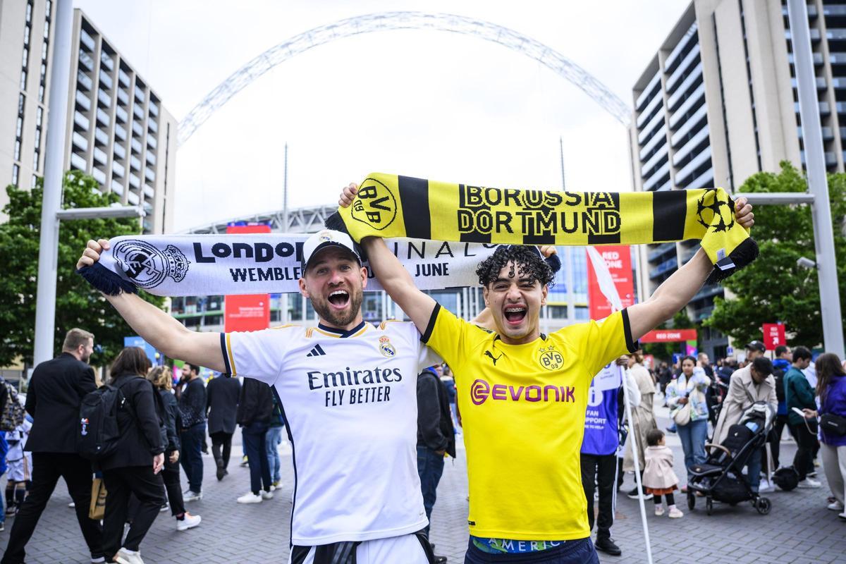 Un fan del Borussia Dortmund y uno del Real Madrid muestran las bufandas de su equipo con el estadio de Wembley a sus espaldas.