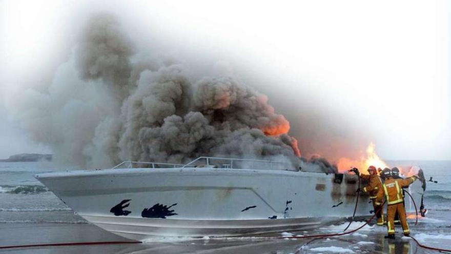 Los servicios de emergencia extinguen el incendio en la planeadora abandonada en A Lanzada. // Muñiz