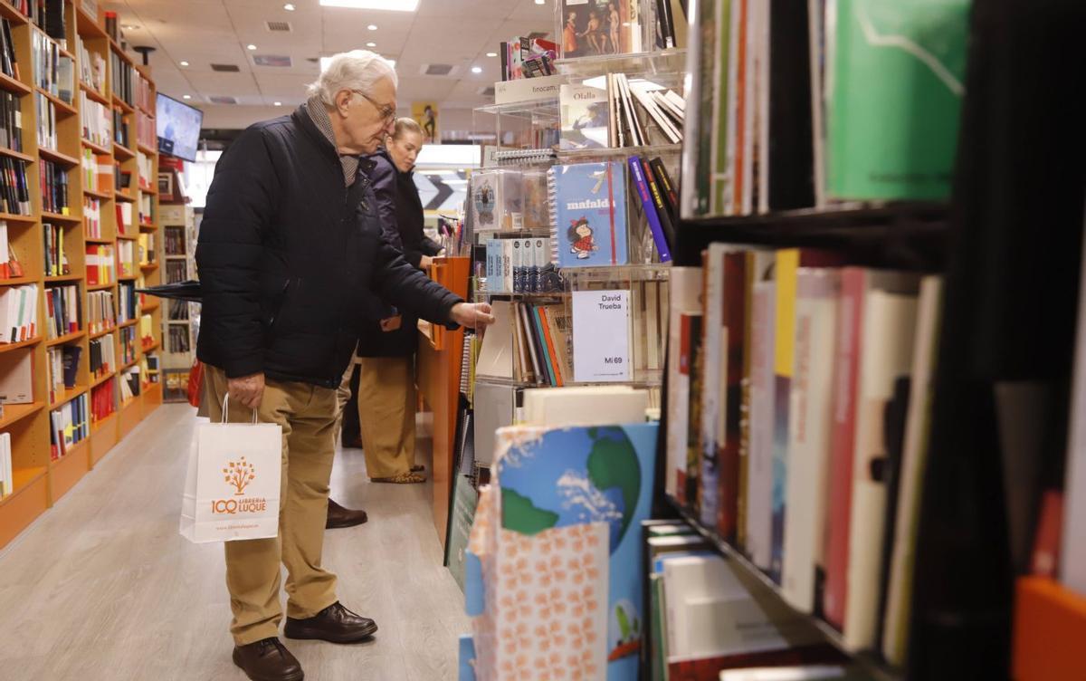 1. El interior de la Librería Luque, con clientes mirando y comprando algunos de sus libros.
2. Maribel Molina, librera y propietaria de El Reino de Agartha, colocando libros.
3. Un estand de algunos de los libros destacados de la Casa del Libro.
4. Un cliente observa uno de los ejemplares de la Casa del Libro. | A.J. GONZÁLEZ