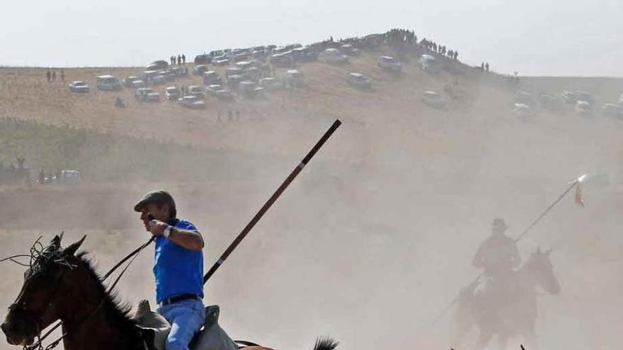 El toro y los caballos envueltos en una nube de polvo.