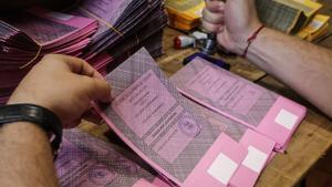 Un hombre prepara las papeletas para la votación de mañana.