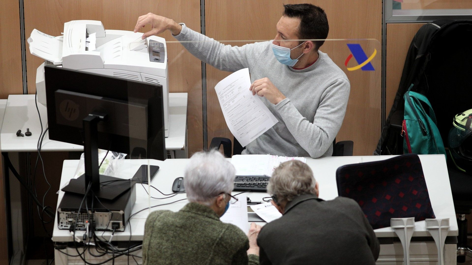 Un trabajador de la Agencia Tributaria de Madrid atiende a dos personas, en junio de 2020.