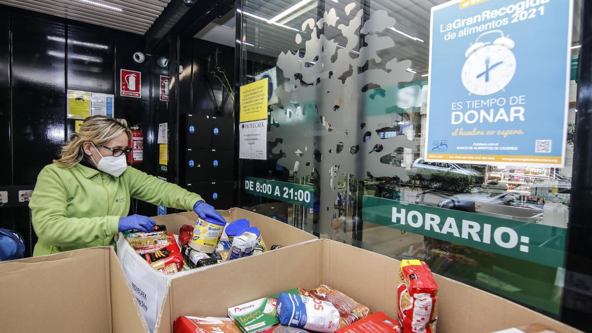 Una trabajadora ayuda a colocar los productos que donan los clientes en las cajas del Banco de Alimentos a las puertas de un supermercado de Cáceres, ayer.