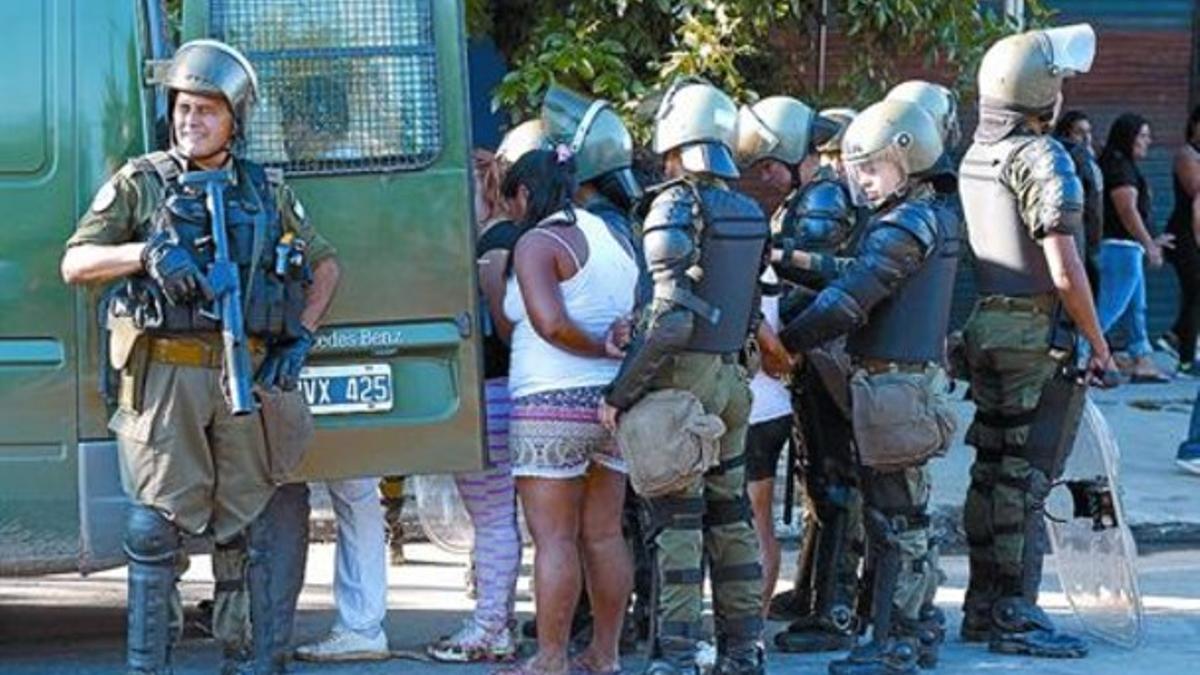 La policía introduce en el furgón a un grupo de detenidos por los saqueos en la ciudad de San Fernando.