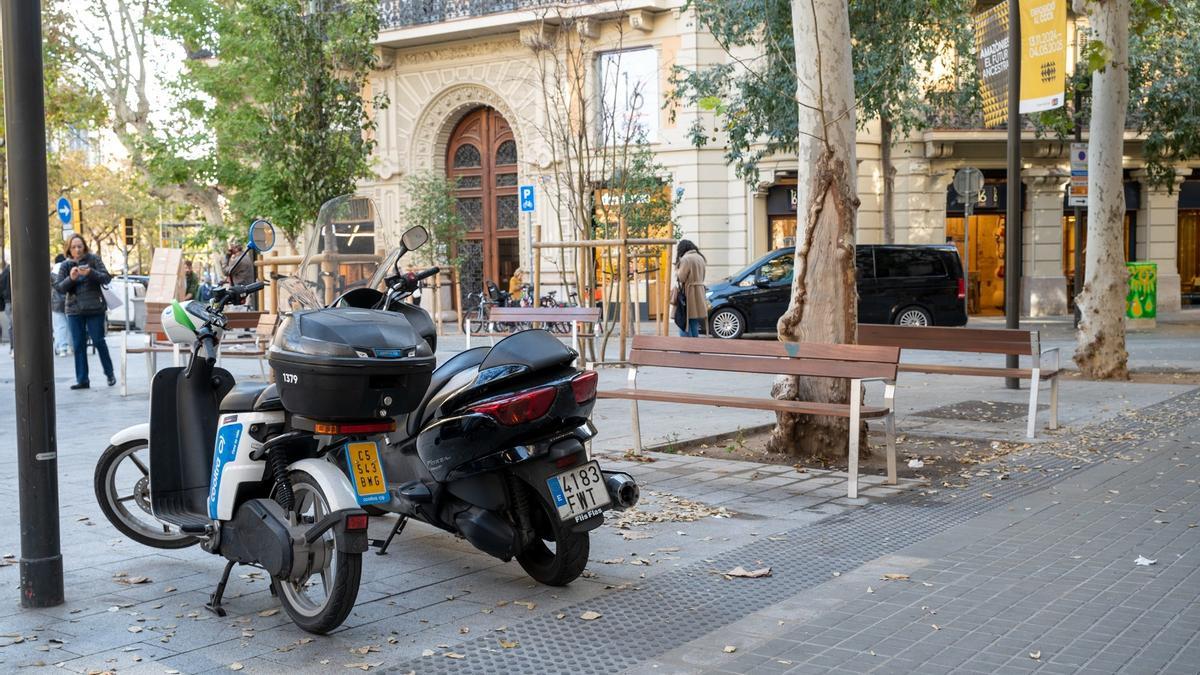 Un par de motos, y a veces más, justo delante de un banco de Consell de Cent.