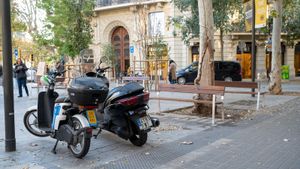 Un par de motos, y a veces más, justo delante de un banco de Consell de Cent.
