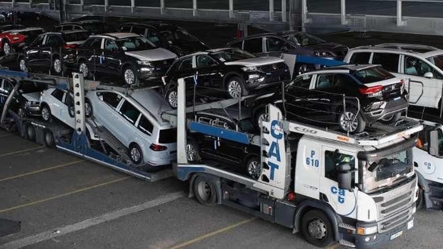 |  La caravana de tráileres cargados con los vehículos producidos por Volkswagen en Portugal comenzó a llegar este viernes a Bouzas tras un trayecto de siete horas de duración. Este tráfico se repetirá a diario con la entrada estimada a la terminal de entre 16 y 20 camiones, con lo que sumarán unos 500 al final el año. En la imagen de arriba, los coches estacionados en la explanada; y en la de abajo, todavía en el camión.