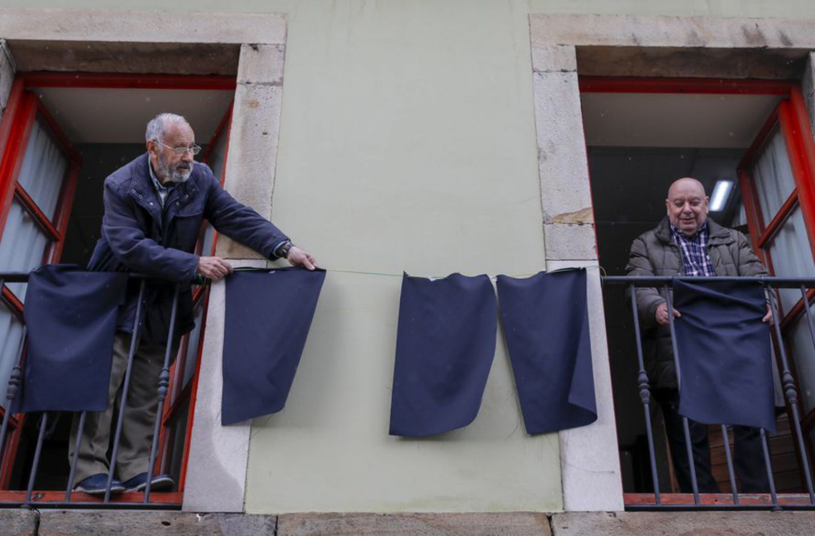 Luciano González y Álvaro Tuero, colocando trapos negros en la asociación vecinal de El Natahoyo.
