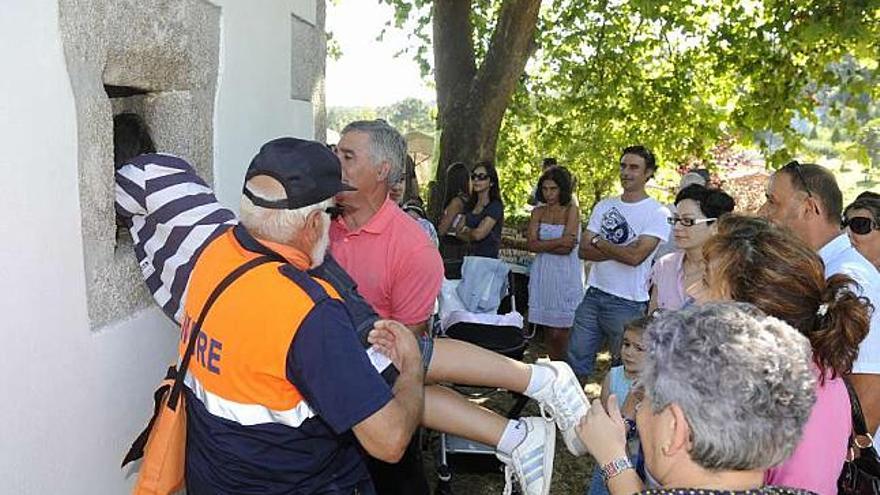 Una persona cumple con la tradición de pasar por el ventanuco de San Juan de Anceis. / víctor echave