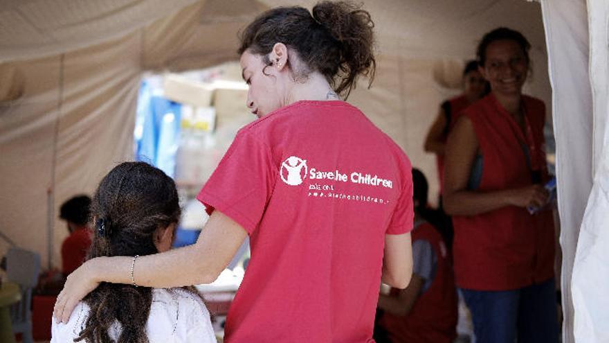 Una miembro de Save the Children, con una niña desalojada por el seísmo.