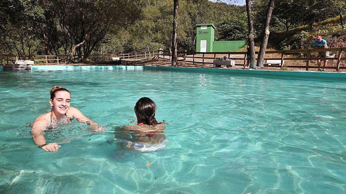 Dos jóvenes se dan un chapuzón en el área de baño de la comunidad de montes de Couso.