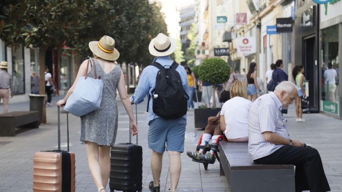 Dos turistas arrastran sus maletas por la calle Cruz Conde.