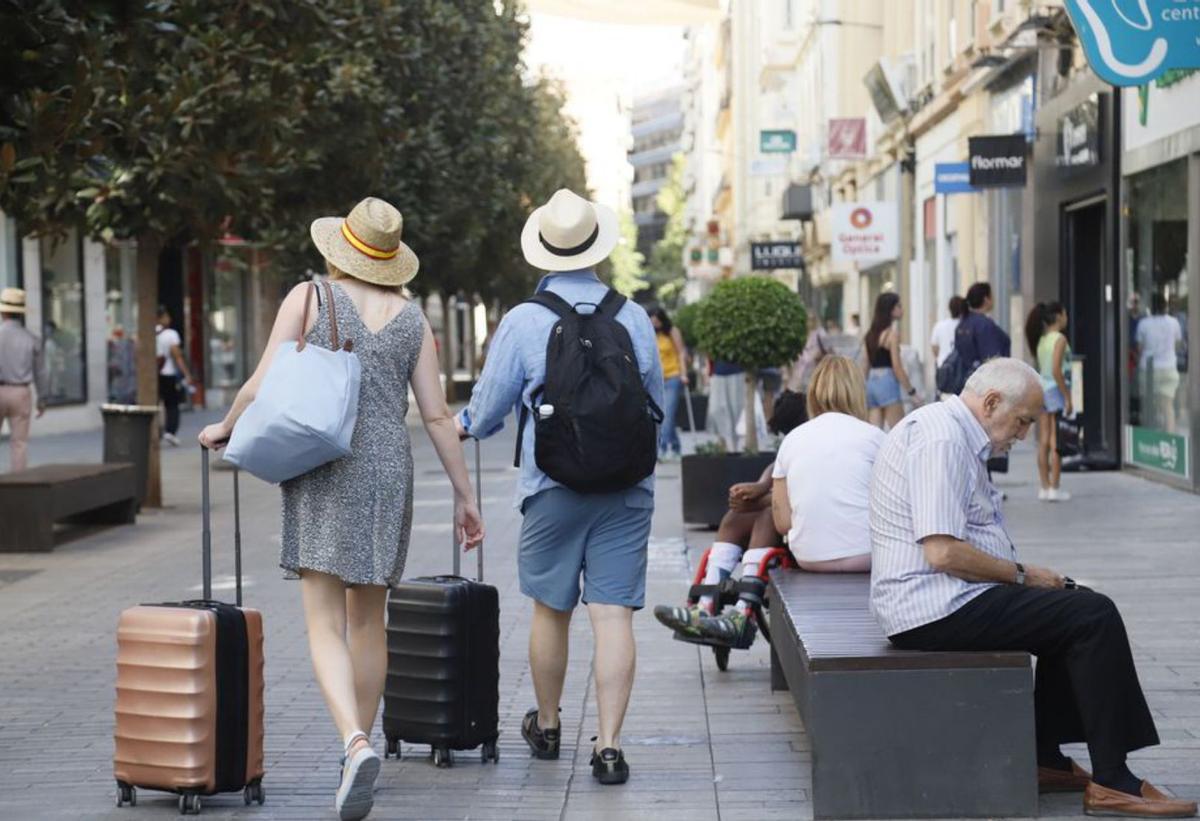 Dos turistas arrastran sus maletas por la calle Cruz Conde.