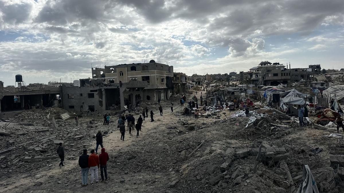 Palestinos inspeccionan el lugar de un ataque israelí contra tiendas de campaña y edificios que albergan a personas desplazadas.