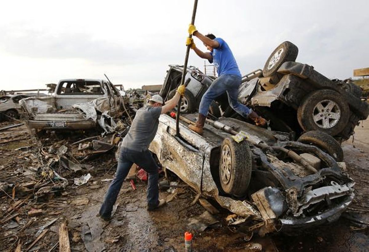 Dos homes intenten obrir la porta d’un cotxe destrossat pel tornado a Moore, aquest dilluns.